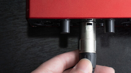 person connecting a microphone cable to an audio interface