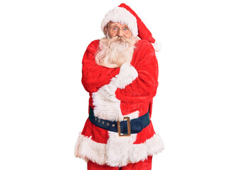 Old senior man with grey hair and long beard wearing traditional santa claus costume shaking and freezing for winter cold with sad and shock expression on face