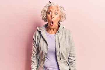 Senior grey-haired woman wearing casual sporty clothes scared and amazed with open mouth for...