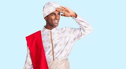 African handsome man wearing tradition sherwani saree clothes very happy and smiling looking far...