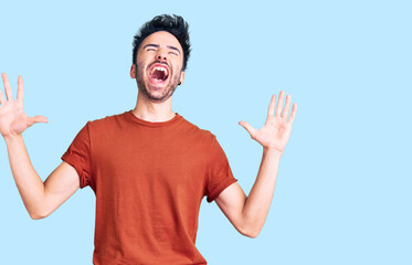Fototapeta premium Young hispanic man wearing casual clothes crazy and mad shouting and yelling with aggressive expression and arms raised. frustration concept.