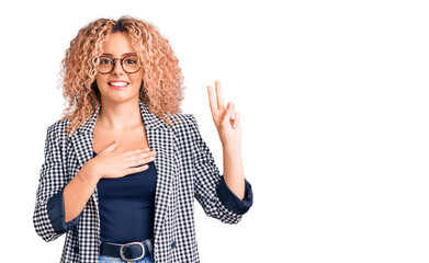 Young blonde woman with curly hair wearing business jacket and glasses smiling swearing with hand...