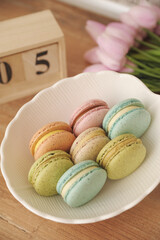 Macarons in white plate on beige background.