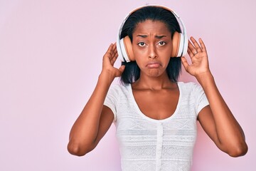 Young african american woman listening to music using headphones depressed and worry for distress, crying angry and afraid. sad expression.