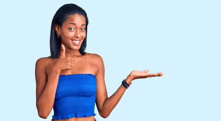 Young african american woman wearing casual summer clothes showing palm hand and doing ok gesture...