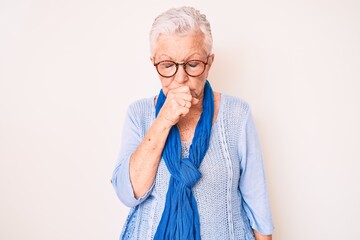 Senior beautiful woman with blue eyes and grey hair wearing casual sweater and scarf feeling unwell and coughing as symptom for cold or bronchitis. health care concept.