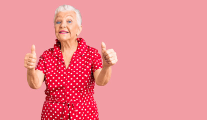 Senior beautiful woman with blue eyes and grey hair wearing a red summer dress approving doing...
