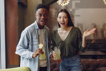 Black man in a cafe. International people. Man in a blue shirt. Woman drinking a cocktail.