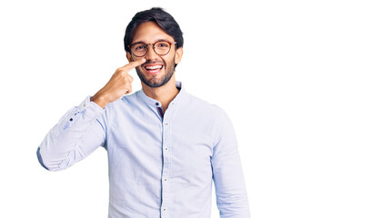 Handsome hispanic man wearing business shirt and glasses pointing with hand finger to face and nose, smiling cheerful. beauty concept