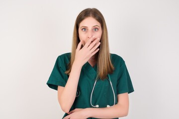 Emotional Female doctor wearing a green scrubs and stethoscope gasps from astonishment, covers...