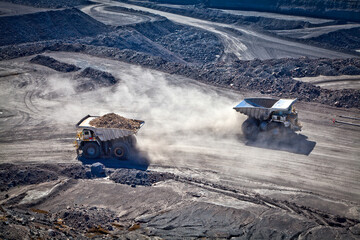 Two diesel-electric trucks used in modern mines and quarries for hauling industrial quantities of ore or coal. Used when extra torque is needed for steep hills. Queensland, Australia. Logos removed.