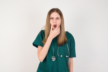 Female doctor wearing a green scrubs and stethoscope Looking fascinated with disbelief, surprise and amazed expression with hands on chin