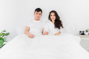 Obraz na płótnie Canvas asian lover rest on bed, asian man holding hand of wife in bedroom, they feeling love and happy together, hands in hands, happiness honeymoon and valentine's day