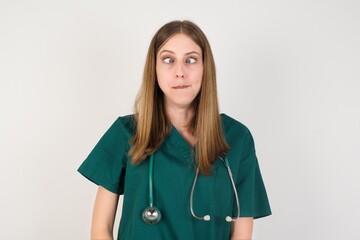 Female doctor wearing a green scrubs and stethoscope making grimace and crazy face, screaming out...
