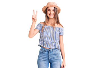 Obraz na płótnie Canvas Young beautiful girl wearing hat and t shirt showing and pointing up with fingers number two while smiling confident and happy.