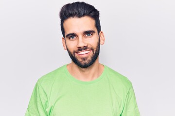 Fototapeta premium Young handsome man with beard wearing casual t-shirt looking positive and happy standing and smiling with a confident smile showing teeth