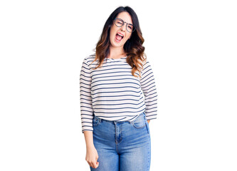 Fototapeta premium Beautiful young brunette woman wearing casual clothes and glasses winking looking at the camera with sexy expression, cheerful and happy face.
