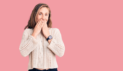 Young beautiful blonde woman wearing casual sweater laughing and embarrassed giggle covering mouth...