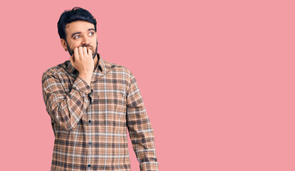 Young hispanic man wearing casual clothes looking stressed and nervous with hands on mouth biting nails. anxiety problem.