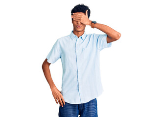 Young african american man wearing casual clothes covering eyes with hand, looking serious and sad. sightless, hiding and rejection concept