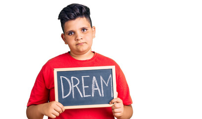 Little boy kid holding blackboard with dream word thinking attitude and sober expression looking self confident