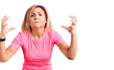 Young blonde woman wearing sportswear shouting frustrated with rage, hands trying to strangle, yelling mad