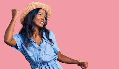 Young indian girl wearing summer hat dancing happy and cheerful, smiling moving casual and...