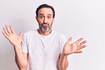 Middle age handsome man wearing casual t-shirt standing over isolated white background clueless and...