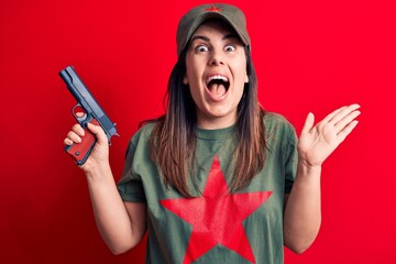 Young beautiful brunette woman wearing t-shirt with red star communist symbol holding gun...