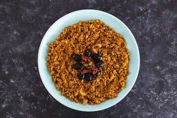 plant-based food, vegan spicy cous cous with moroccan spices and turmeric with kalamata olives and sundried tomatoes topping