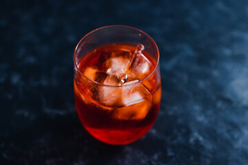 refreshing red spritz cocktail with ice on dark background