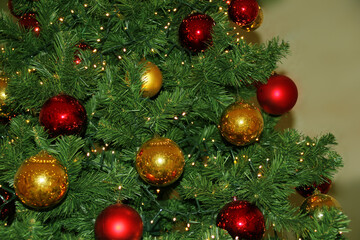 Obraz na płótnie Canvas green christmas tree with red and yellow balls, with lights and highlights, festive concept, form for greeting card, copy space