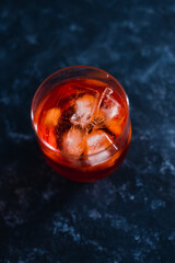 refreshing red spritz cocktail with ice on dark background