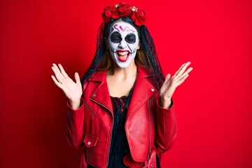 Woman wearing day of the dead costume over red celebrating mad and crazy for success with arms raised and closed eyes screaming excited. winner concept
