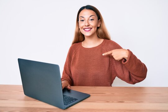 Young brunette woman working using computer laptop pointing finger to one self smiling happy and proud
