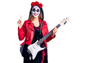 Obraz na płótnie Canvas Woman wearing day of the dead costume playing electric guitar surprised with an idea or question pointing finger with happy face, number one