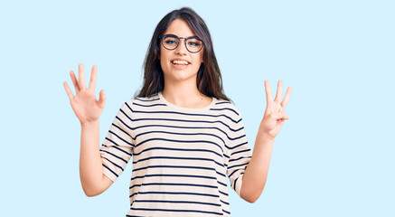 Brunette teenager girl wearing casual clothes and glasses showing and pointing up with fingers number eight while smiling confident and happy.