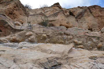 Side of stony cliff with multiple geologic layers of sedimentary rock