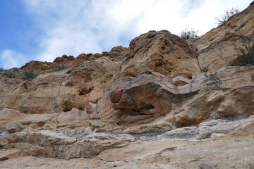 Fototapeta premium Rocky cliff with jagged sandstone and blue sky overhead