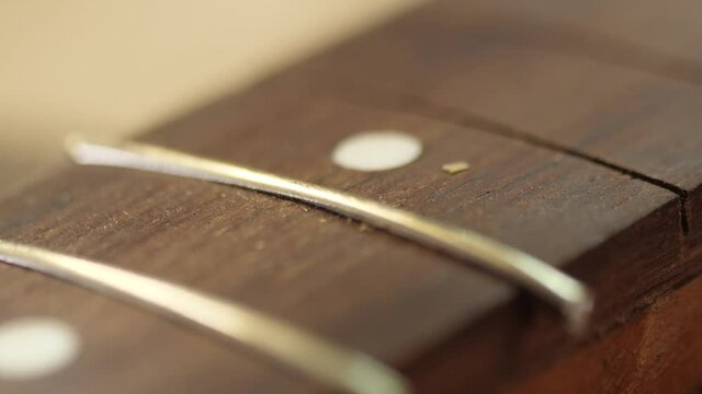 Craftsman artisan fitting in brass fret wood guitar fingerboards slow motion 4k
