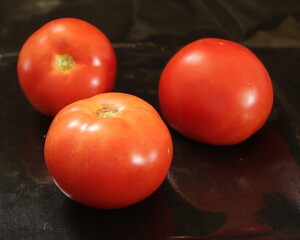 Three red tomatoes on a black background