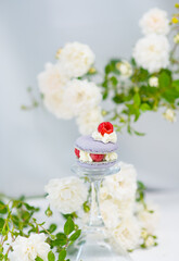 Macaroon cake with raspberries lies on a glass toast against a background of roses