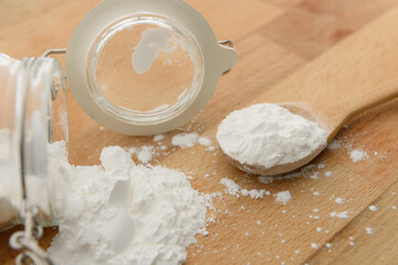 Close-up of tapioca starch or flour powder in wooden spoon with wooden background