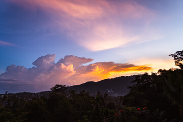 Spectacular sunset sky over valley with trees, city and mountains. View from the top.