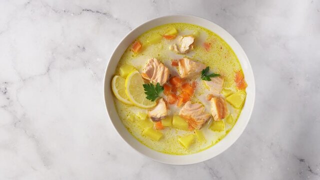 A single plate with delicious salmon cream soup on white background captured from above. Top view. Rotation from left to right. 4K UHD video