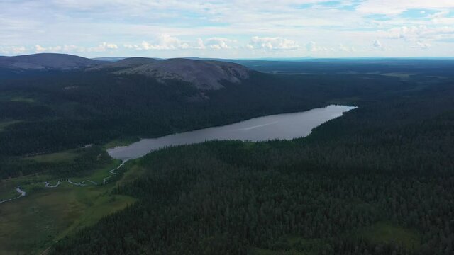 Aerial view tilting towards lake Kesankijarvi and the Kesanki fell, on a gloomy, summer day, in Pallas-Yllastunturi national park, Kolari, Lapland, Finland - reverse, drone shot