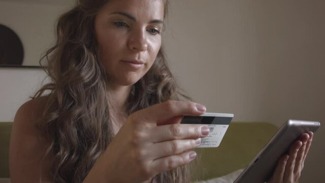 Young caucasian woman using master card and digital tablet while shopping at home. Woman shopping at home. Woman buys online.