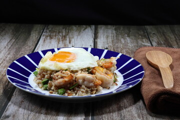 Traditional fried and stirred cooked rice with cutting green bean, fresh peeled shrimp and chopped pork sausage on the plate topping with fried egg. Famous special breakfast in the morning in Asia. 