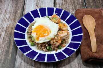 Traditional fried and stirred cooked rice with cutting green bean, fresh peeled shrimp and chopped pork sausage on the plate topping with fried egg. Famous special breakfast in the morning in Asia. 