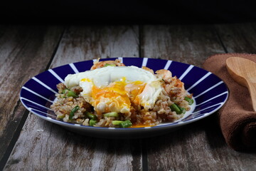 Traditional fried and stirred cooked rice with cutting green bean, fresh peeled shrimp and chopped pork sausage on the plate topping with fried egg. Famous special breakfast in the morning in Asia. 